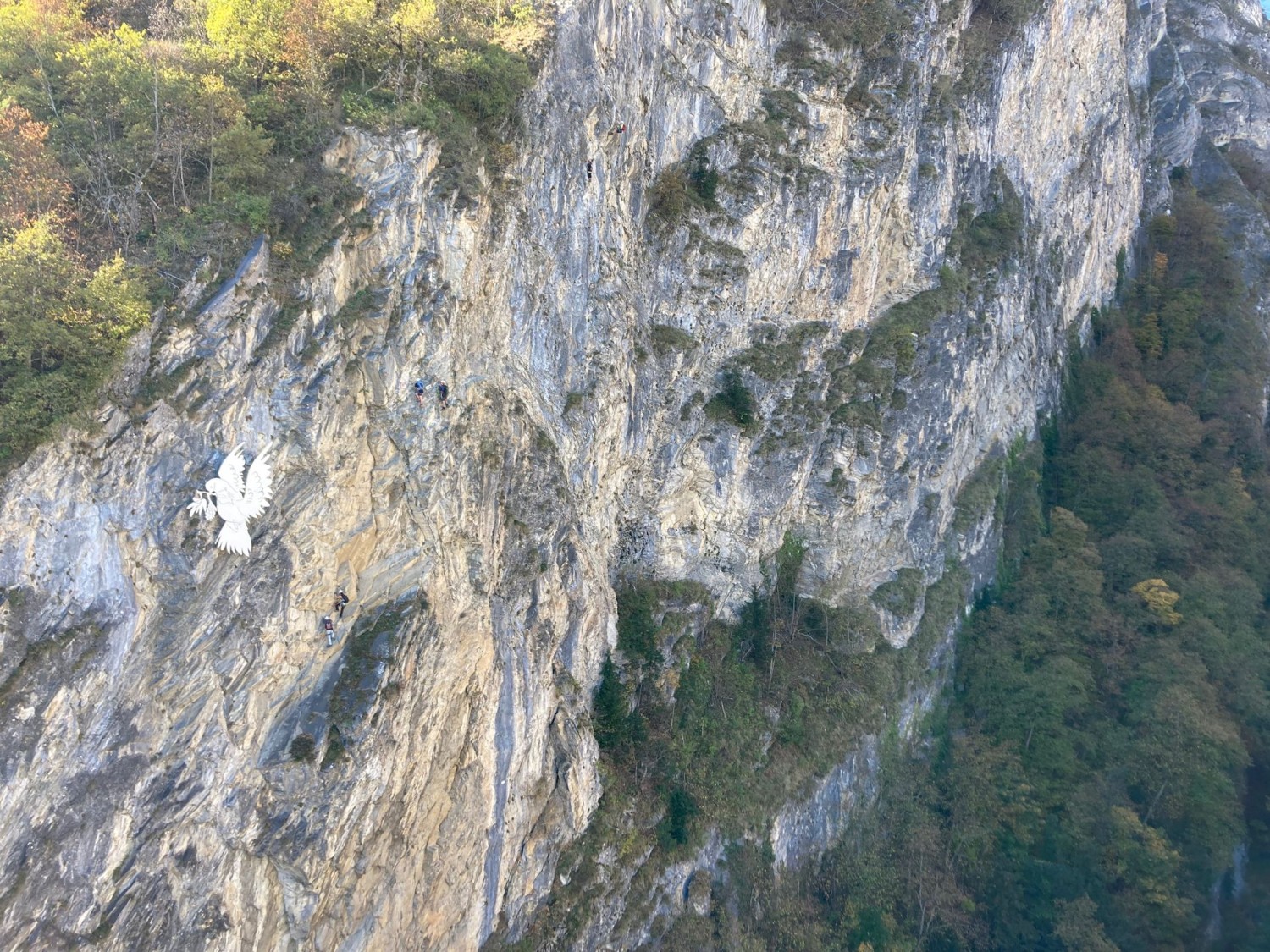 Sous la sculpture d’oiseau, celles et ceux qui escaladent la Via Ferrata sont minuscules.