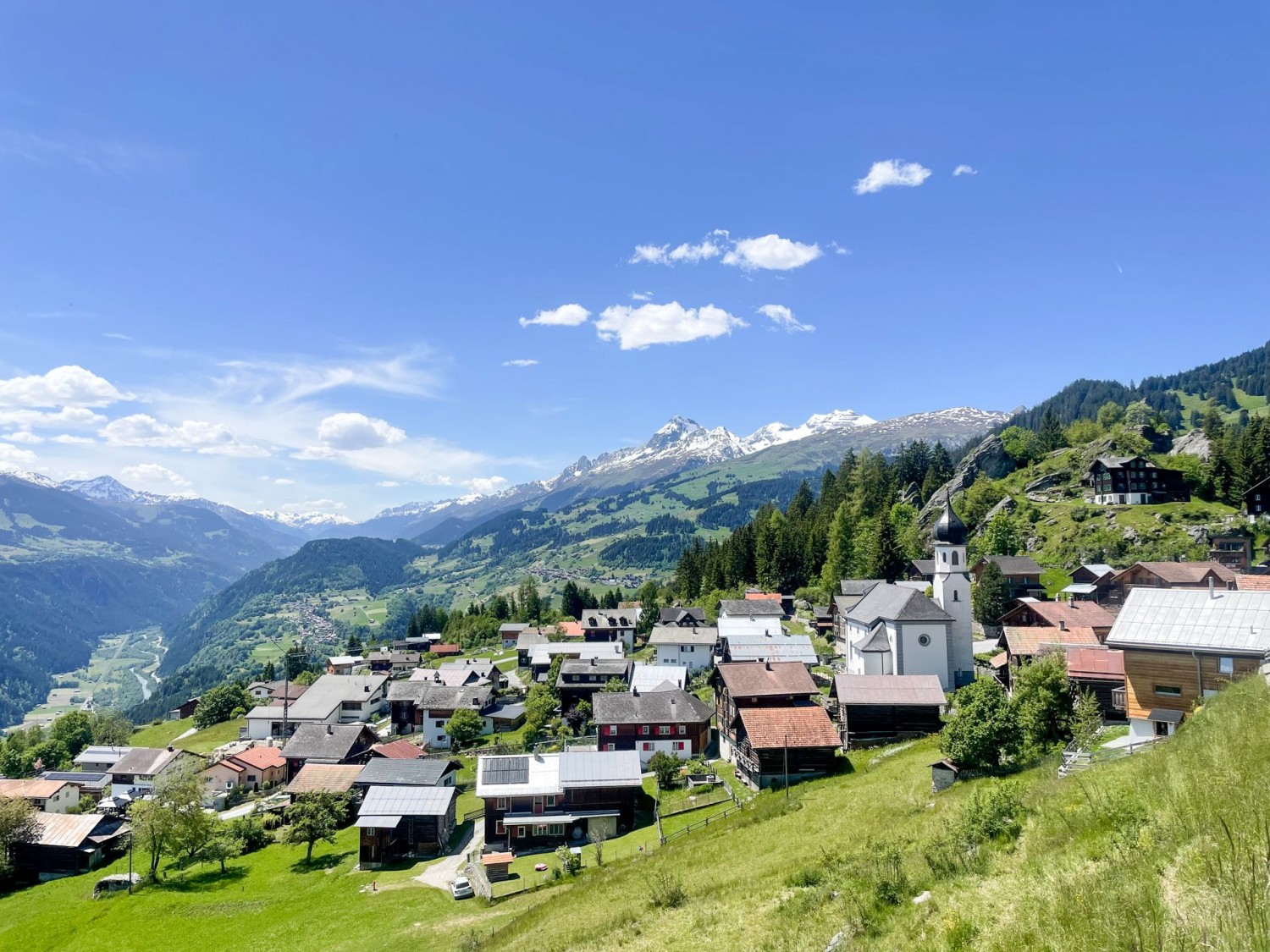 Vue sur le village de montagne ensoleillé de Siat et sur le Rhin antérieur.