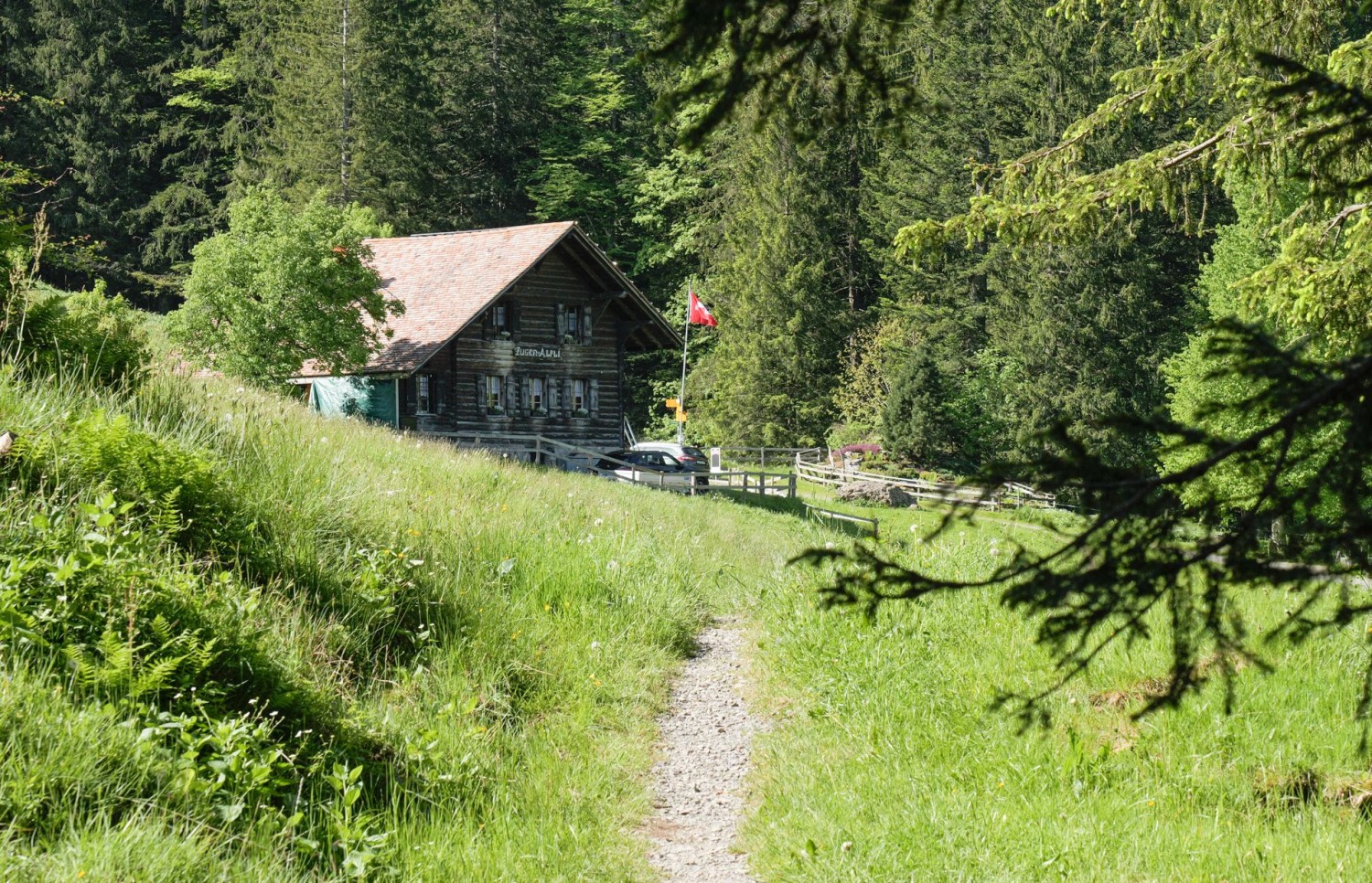 Le sommet du Wildspitz et l’auberge de montagne. Derrière le drapeau suisse, le Hoflue, et les Alpes de Suisse centrale en arrière-plan